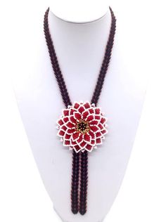 a red and white beaded flower necklace on a mannequin headpiece,