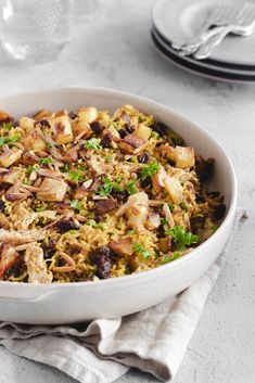 a bowl filled with rice and vegetables on top of a white tablecloth next to a napkin