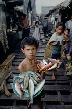 a young boy holding a plate full of fish