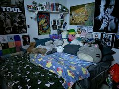 a bed with lots of stuffed animals on top of it in a room filled with posters