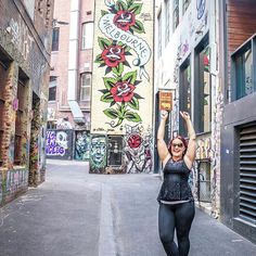 a woman is walking down the street with her arms in the air while holding up a book