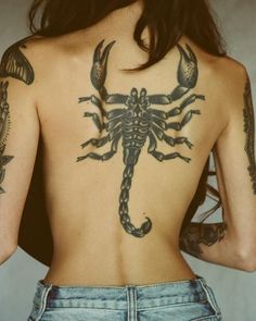 the back of a woman's body with scorpion tattoos on her upper and lower half