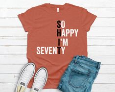 an orange shirt that says so happy i'm sixty five next to some jeans