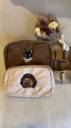 two small purses sitting on top of a bed next to a teddy bear and dried flowers