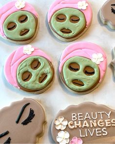 decorated cookies with green and pink icing on top of a white tablecloth that says beauty changes lives