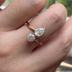 a woman's hand with two engagement rings on her left and the ring is gold