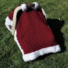 a red and white knitted santa hat laying on the grass