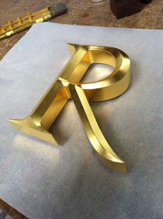 the letter p is made out of gold foil and sits on top of a piece of paper