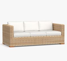 a wicker couch with white cushions