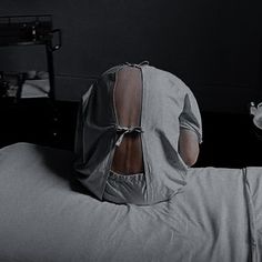 a woman laying in bed with her back turned to the camera and covering her face