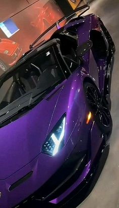 a purple sports car is parked in a garage with its hood up and lights on