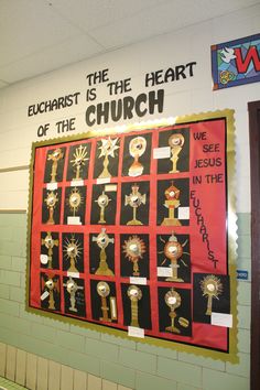 a bulletin board with medals on it in a school hallway that reads, euchatist is the heart of the church we see jesus in the name