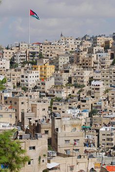 a city with lots of tall buildings and a flag flying high in the sky above