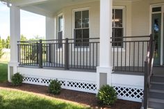 the front porch of a house with white siding and black iron railings on it