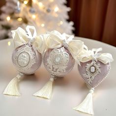 three ornaments are sitting on a table near a christmas tree