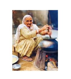 an old woman sitting on the ground next to a pot