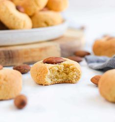 some almonds are on the table and one has a bite taken out of it