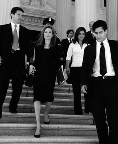 two women and one man are walking up the stairs in front of an official building