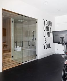 an indoor sauna with glass walls and black accents on the wall, along with a bike