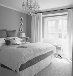 black and white photograph of a bedroom with chandelier, bed, and window