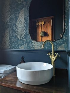 a white bowl sink sitting on top of a wooden counter next to a bathroom mirror