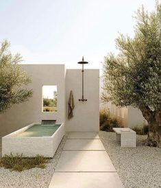 an outdoor shower in the middle of a graveled area with trees and benches around it