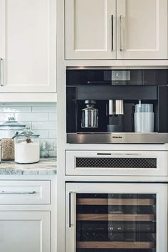 a kitchen with white cabinets and stainless steel appliances, including a built - in wine cooler