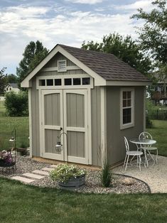 a small shed with a table and chairs in the front yard, surrounded by grass