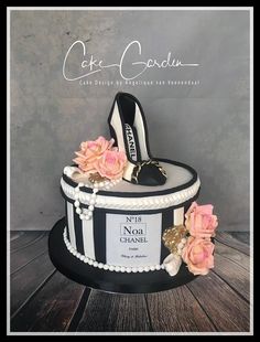 a black and white cake with pink flowers on the top is decorated with high heel shoes