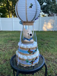 a cake made to look like a teddy bear sitting in a hot air balloon with diapers on it