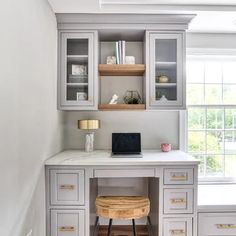 a home office with built - in desk, shelves and drawers on either side of the window