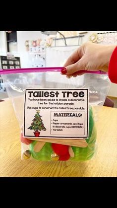 a plastic bag filled with christmas trees on top of a wooden table next to a person's hand