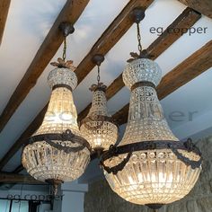 three chandeliers hanging from the ceiling in a room with exposed wood beams and stone walls