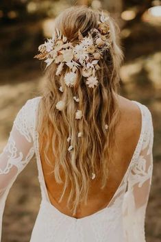 the back of a woman's head with long hair and flowers in her hair