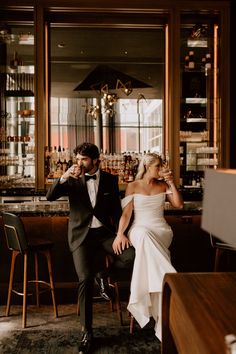 a bride and groom sitting at a bar