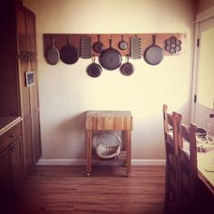 a kitchen with pots and pans hanging on the wall next to a wooden table