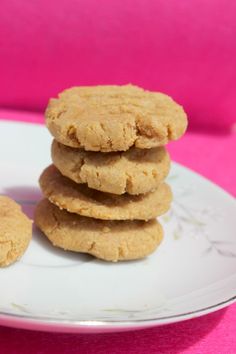 a stack of cookies sitting on top of a white plate next to a pink wall