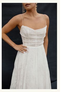 a woman is wearing a white dress and has her hands on her hips