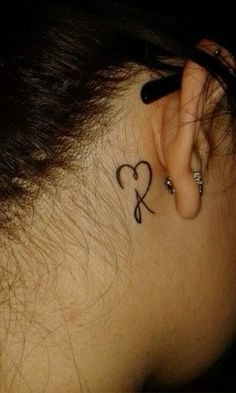 a woman's ear with a heart tattoo on her left side behind the ear