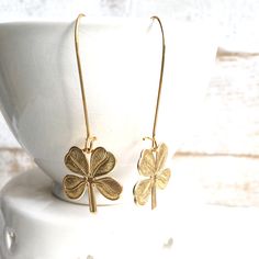 These are super cute lucky shamrock earrings. These fun good luck four leaf clover brass charms hang from simple ear wires Each earring measures approx 2 1/2 inches from the top of the ear wire to the bottom of the charms. Clover charms measures just under 1 inch by 1 inch. The three leaves of a shamrock are also said to stand for faith, hope and love. A fourth leaf is uncommon and considered to be a symbol of good luck. Matching necklace available here- https://www.etsy.com/listing/947083441/lu Brass Charm Earrings As Gift, Gold Jewelry For St. Patrick's Day Gift, Brass Earrings With Charms For Gifts, Brass Earrings With Charms As Gift, Brass Earrings With Dangling Charms As Gift, Irish Earrings, Shamrock Earrings, Celtic Earrings, Lucky Shamrock