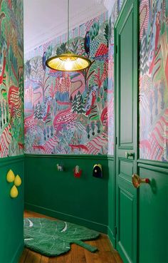 a room with green walls and colorful wallpaper on the walls, along with wooden flooring