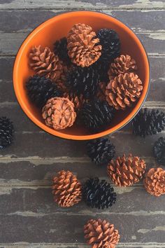 a bowl filled with pine cones on top of a wooden table