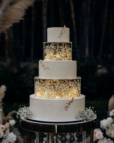 a three tiered wedding cake with lights on it