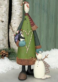 a wooden christmas tree with two snowmen next to it