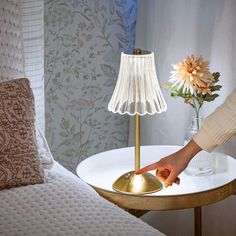 a table with a lamp on it and a person reaching for something in the bowl