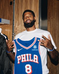 a man holding up a basketball jersey in front of a wooden wall with his hands