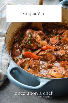 a blue pot filled with shrimp and carrots next to a wooden spoon on top of a table