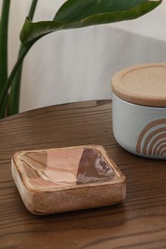 a wooden table topped with a white container and a small bowl on top of it