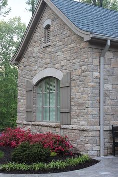 a brick house with flowers in the front yard