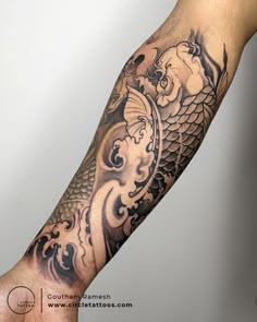 a man's arm with a dragon and fish tattoo on the left side of his arm